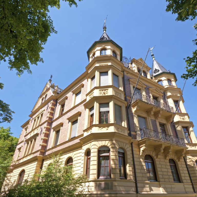 Beeindruckende Hausarchitektur Historisches Gebäude mit Türmen und verzierten Fassaden unter klarem blauen Himmel.